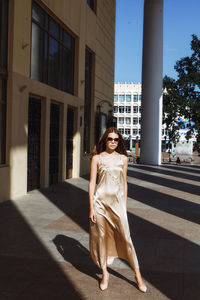 Full length of fashionable young woman standing by building in city