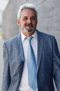 Mature businessman walking against gray wall