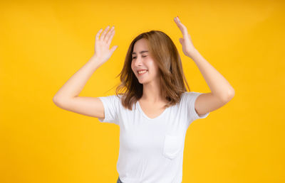 Portrait of a smiling young woman against yellow background