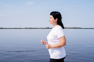 Side view of man standing in lake against sky