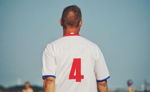 Rear view of man standing against blue sky