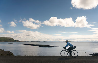 Side view of person cycling by the sea
