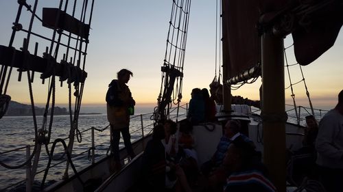 People on sailboat at sea against sky