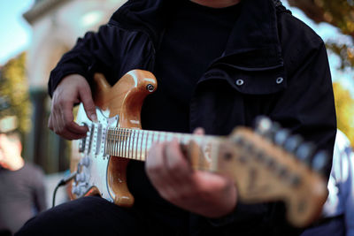 Midsection of man playing guitar