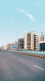 Road by buildings against sky in city