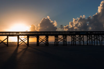 Silhouette pier at beach against sky during sunset