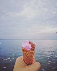 Close-up of hand holding ice cream on beach