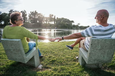 Friends sitting on shore against sky