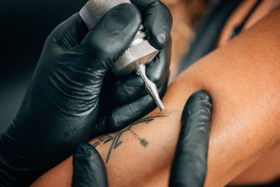 Cropped image of person tattooing on hand