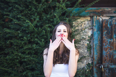 Beautiful young woman sitting near farmer house, smiling, sending air kiss. spring or summer season 