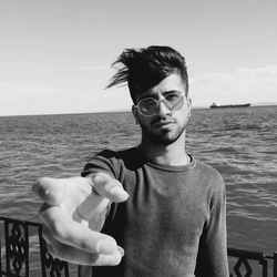 Portrait of young man standing against sea