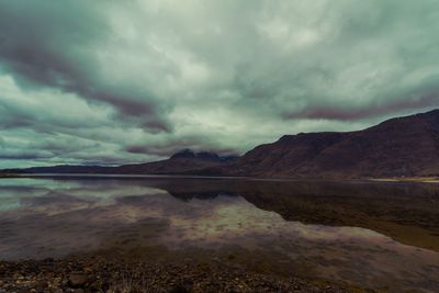 Scenic view of lake and mountains against cloudy sky