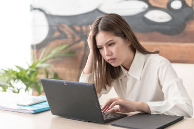 Young woman using phone while sitting on table