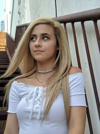 Low angle view of teenage girl sitting by railing on staircase