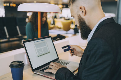 Midsection of man using mobile phone while sitting on table