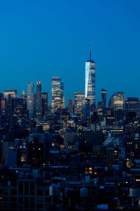 Illuminated cityscape against clear blue sky at night