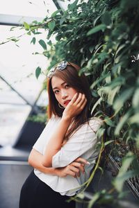 Portrait of beautiful young woman standing by plants