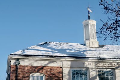 Low angle view of lighthouse against building against clear blue sky