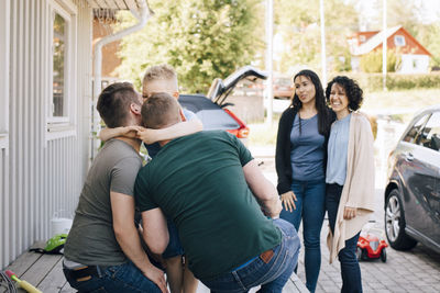 Fathers embracing son while lesbian couple standing outdoors during weekend