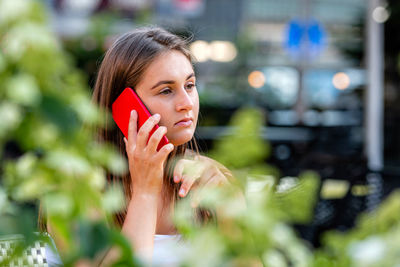 Close-up of young woman talking on phone while looking away standing away