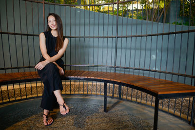 Portrait of woman sitting on railing