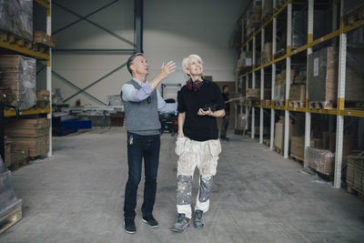 Senior man discussing with colleague while looking at wooden planks industry