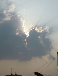 Low angle view of electricity pylon against cloudy sky