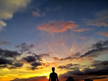 Rear view of silhouette man standing against sky during sunset