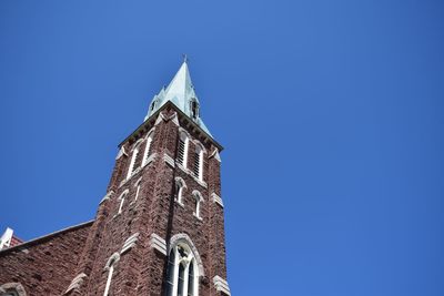 Low angle view of clock tower against blue sky