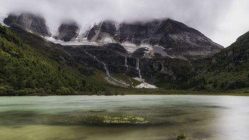 Scenic view of lake by mountains against sky