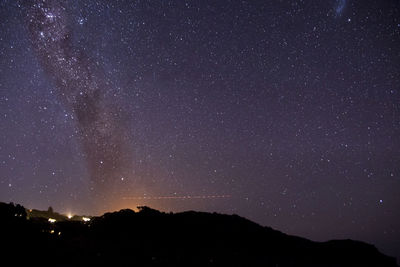 Silhouette mountain against star field at night