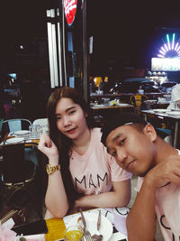 Portrait of happy woman sitting in restaurant at night