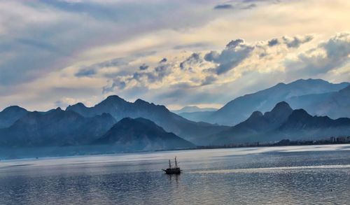 Scenic view of sea by mountains against sky