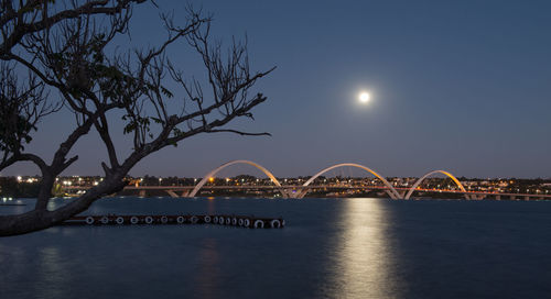 Illuminated bridge over river against sky