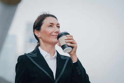 Close-up of mature woman holding coffee cup while standing outdoors