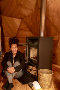 Joyful and relaxed woman sitting next to fireplace.