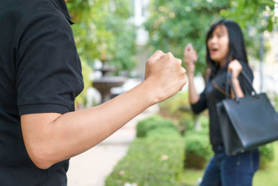 Midsection of couple holding hands standing outdoors