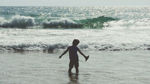 Rear view of boy in sea on sunny day