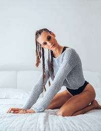 Portrait of young woman with braided hair sitting on bed 