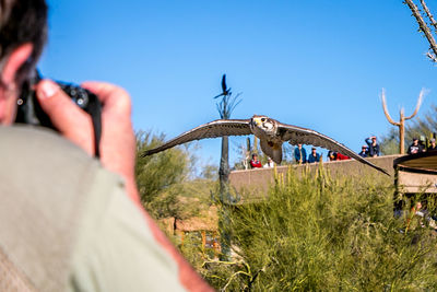 Close-up of man photographing against clear sky