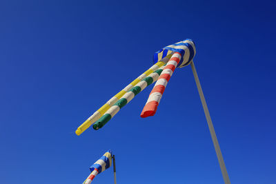 Low angle view of kites against clear blue sky