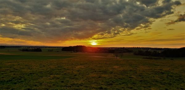 Scenic view of dramatic sky over land during sunset