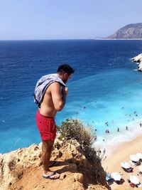 Full length of man on rock at beach against sky