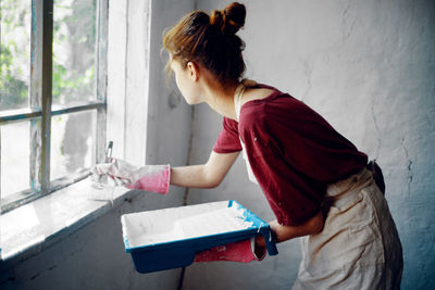 Side view of woman working on window