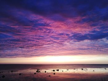 Scenic view of sea against dramatic sky during sunset