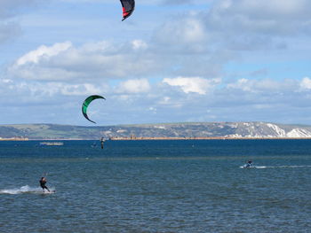 People flying over sea against sky