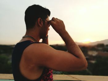Close-up of young woman with sunglasses against sky during sunset