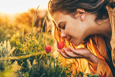 Close-up of woman smelling flower on field