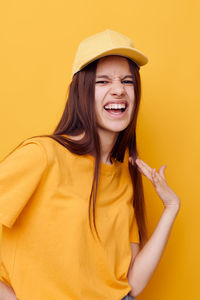 Portrait of beautiful young woman standing against yellow background