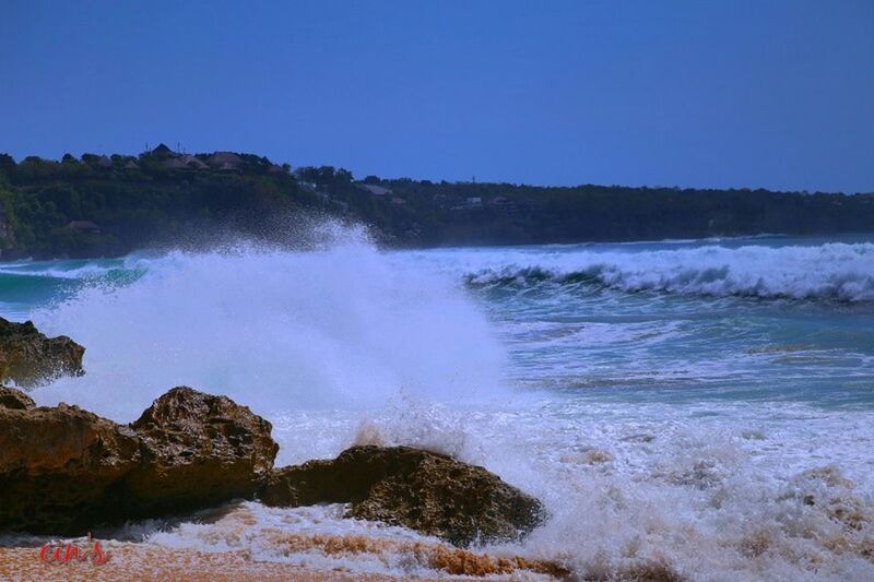 WAVES SPLASHING ON ROCKS AGAINST BLUE SKY